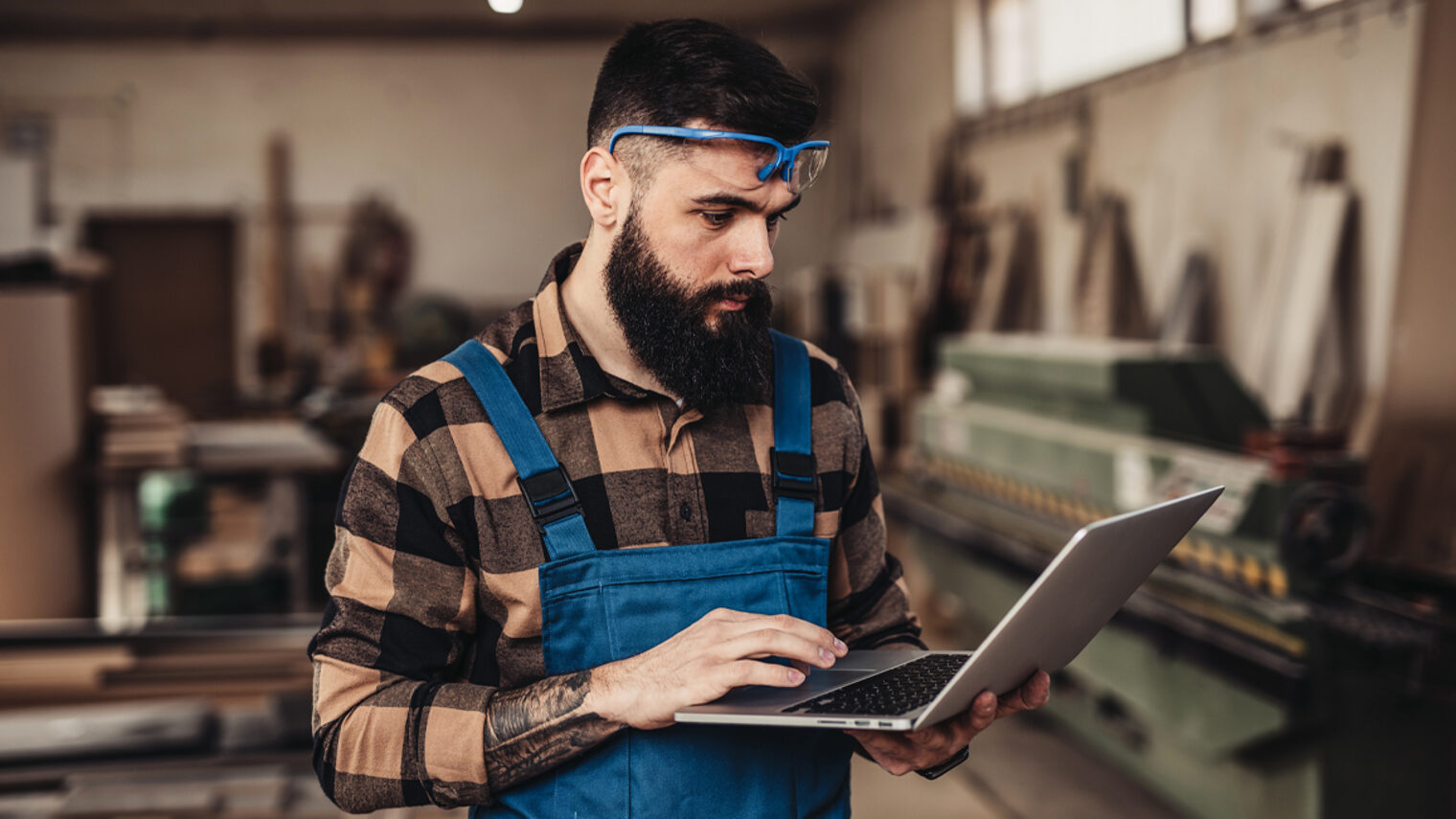 Mann in Werkstatt mit Laptop in der Hand
