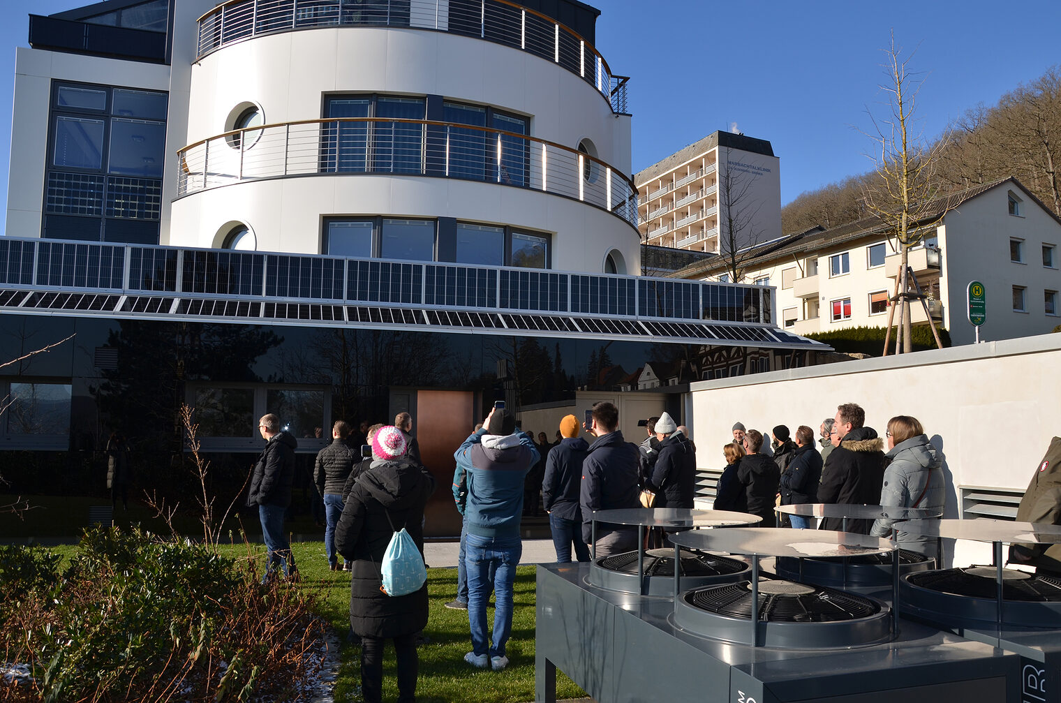 Gruppe steht vor Haus, welches verschiedene Photovoltaikarten hat