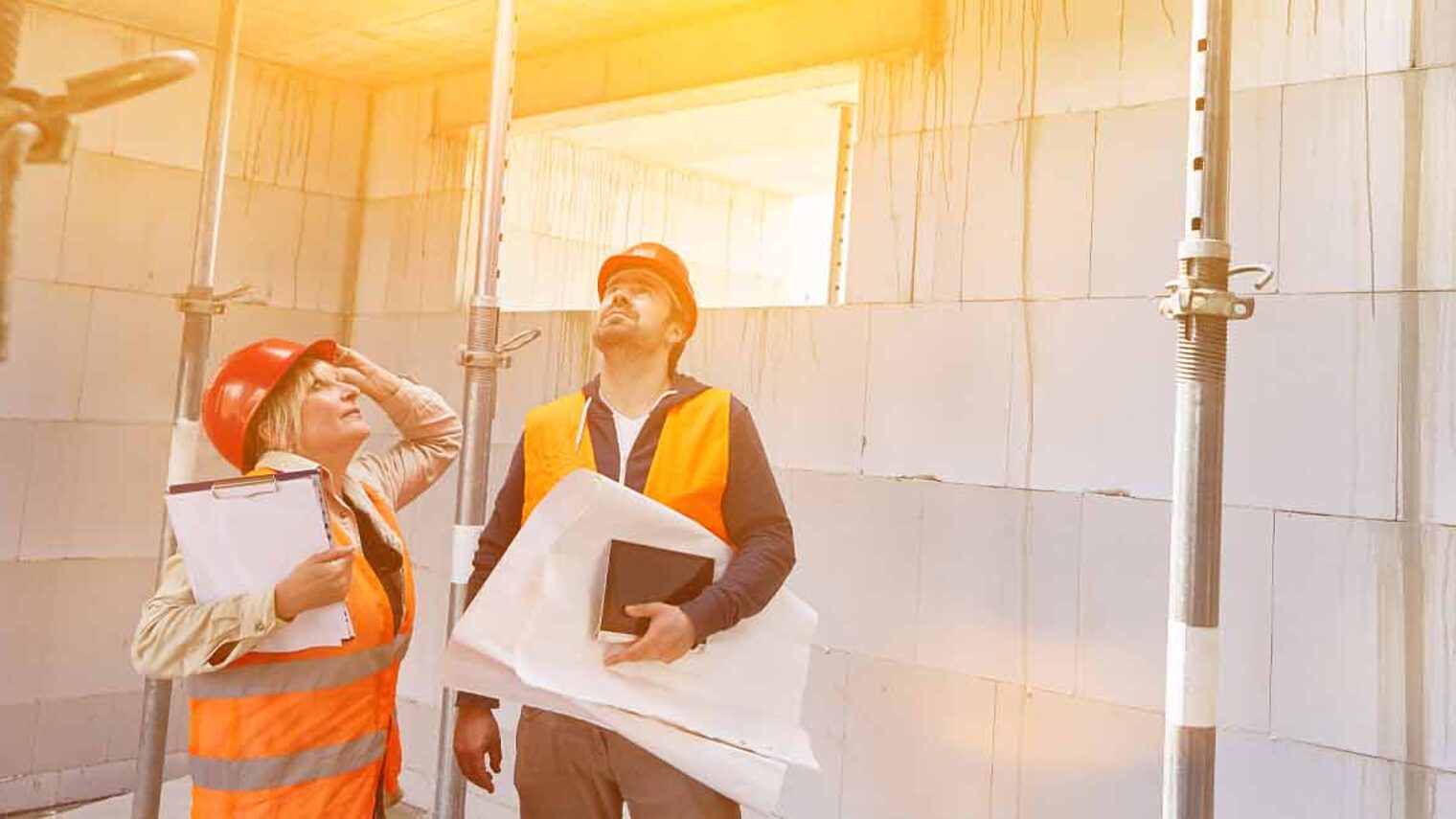 Zwei Sachverständige auf einer Baustelle begutachten das Mauerwerk