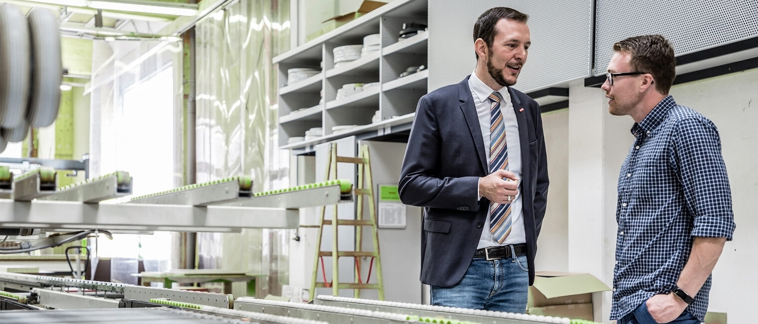 Unternehmensberatung Berater und Betriebsinhaber in Werkstatt im Gespräch