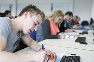 Nahaufnahme von Schüler an einem Tisch, der mitschreibt