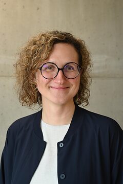 Portrait: Frau mit Locken und runder Brille lächelt in die Kamera Portrait: Frau mit Locken und runder Brille lächelt in die Kamera