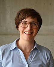 Frau in hellblauer Bluse mit kurzen braunen Haaren lächelt Frau in hellblauer Bluse mit kurzen braunen Haaren lächelt in die Kamera