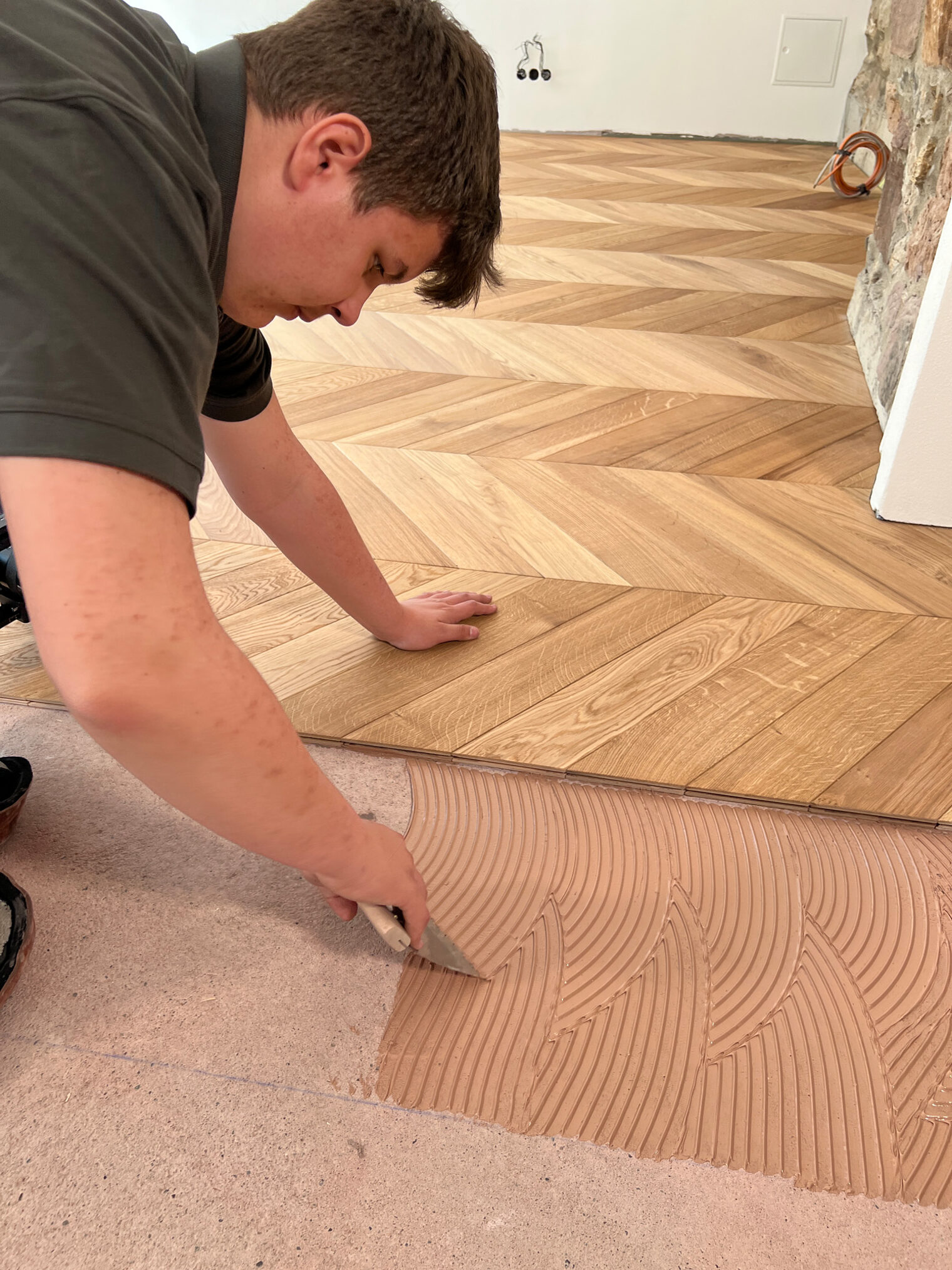 DMH 2025 | Kammersieger Parkettleger am Boden, trägt Leim für Holz auf