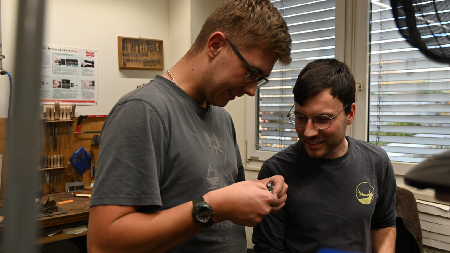 Zwei Männer in einer Werkstatt, schauen gemeinsam auf ein Werkstück