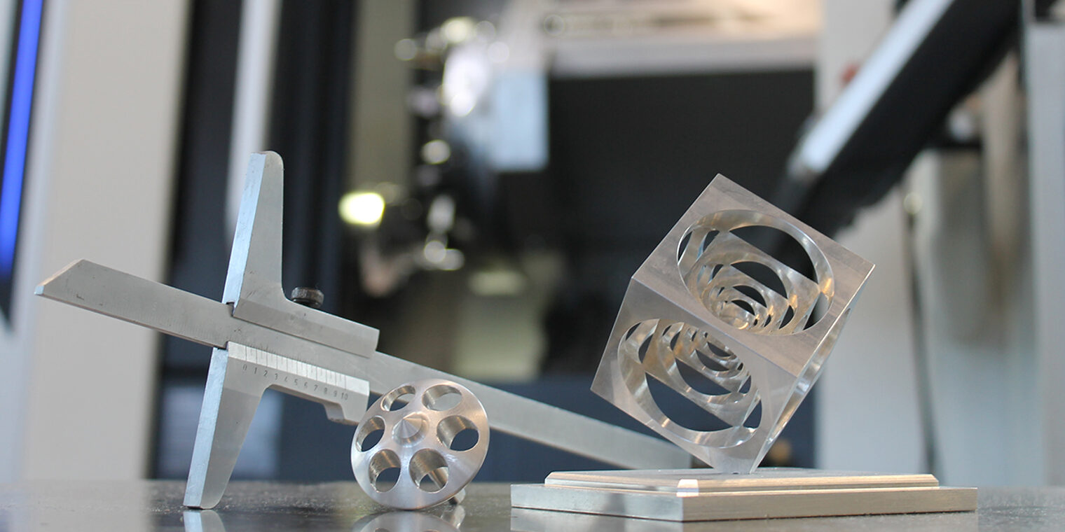 Präzisionsarbeit im Meisterkurs: Messschieber, gefräste und gedrehte Metallstücke vor moderner Drehmaschine