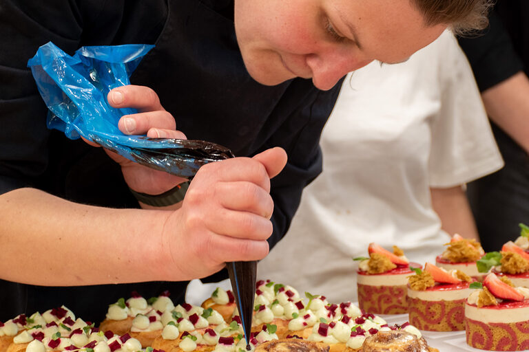 Meisterschülerin beim Ausdekorieren der Eclairs mit Rote Beete und Rucola